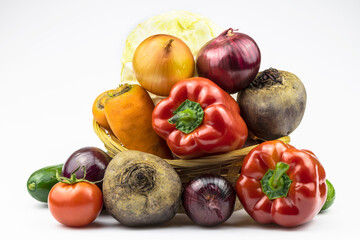 An assortment of vegetables for healthy eating in a wicker basket close-up isolated on a white background.