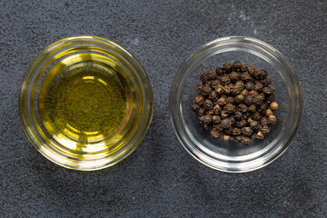 Black papper corn spice and olive oil in bowl on dark background