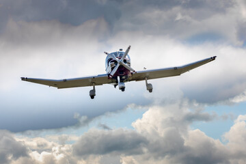 Fototapeta na wymiar a small blue plane flying through clouds on landing approach