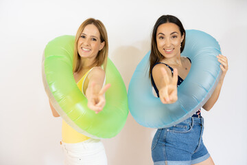 Portrait of a two pretty girls dressed in swimsuits holding ring inflatable isolated over white background