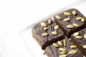 flourless pumpkin chocolate brownies set on white cafe table.