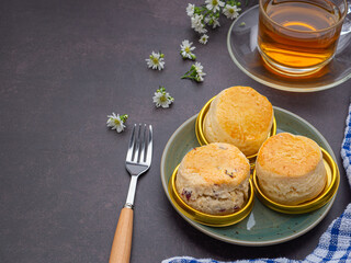 English style scones delicious freshly baked homemade and strawberry jam on a plate with a cloth and a teacup on the old kitchen table. Space for text. Dessert and beverage concept