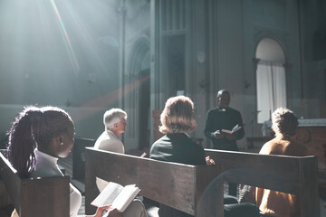 Group of people listening to priest during Sunday mass in the church