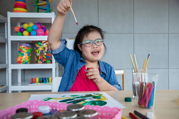 Young girls disabilities Or Down's syndrome holding paint brush for painting watercolor and bright...