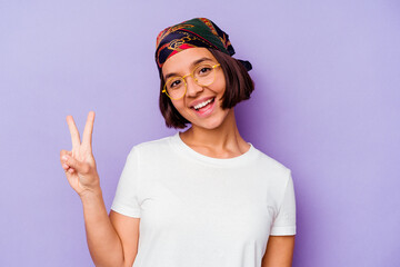 Young mixed race woman wearing a bandana isolated on purple background joyful and carefree showing a peace symbol with fingers.