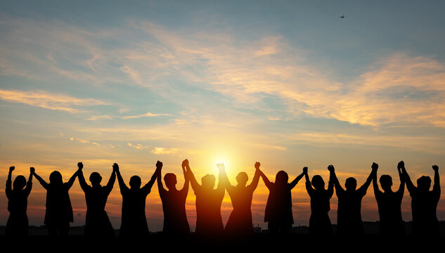 Silhouette of group business team making high hands over head in sunset sky