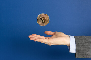 Fototapeta na wymiar Person hand and bitcoin cryptocurrency over blue background.