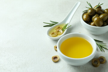 Bowls with olives and oil on white textured background