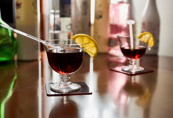 Cocktail glasses with vermouth and lemon, and various bottles