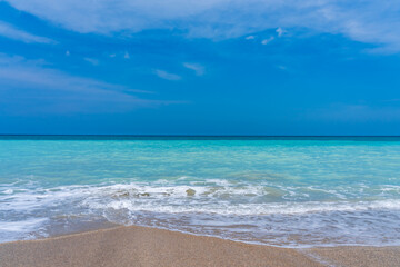 Panorama of an ocean beach in Florida in the spring. Turquoise ocean and a shallow white wave runs over the sand