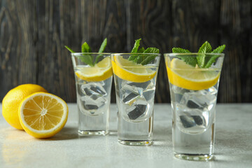 Shots with lemon slice and mint on white textured table