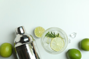Glass of cocktail with lime and ingredients on white background