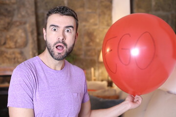 Man holding large red balloon representing his ego