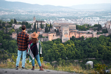 A young traveling couple on their honeymoon contemplate the views of the Alhambra palace in the city of Granada, Spain
