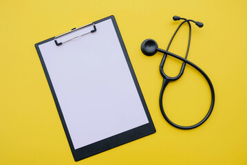 Black stethoscope and blank medical form on yellow background. Medicine and healthcare concept....
