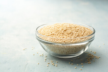 White sesame seeds in glass bowl on concrete background
