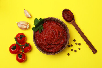 Bowl of tomato paste and ingredients on yellow background