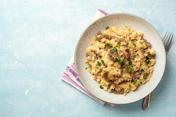 Risotto with mushrooms, parmesan cheese and parsley in plate on concrete background