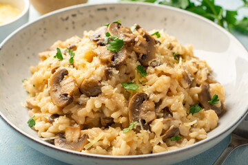 Risotto with mushrooms, parmesan cheese and parsley in plate on concrete background