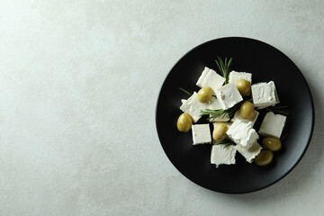 Obraz na płótnie Canvas Plate with feta cheese, olives and rosemary on white textured background