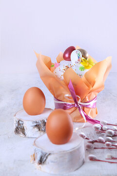 Easter cake in a festive package on a light background. Willow branches.Concept of the Easter holiday. Free space. Chicken eggs on wooden stands. Vertical photo.