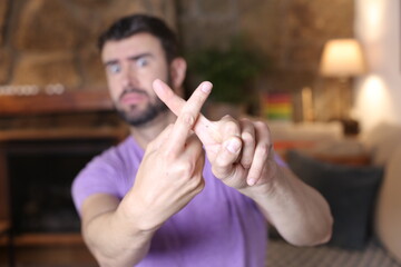 Angry man crossing fingers as rejection sign