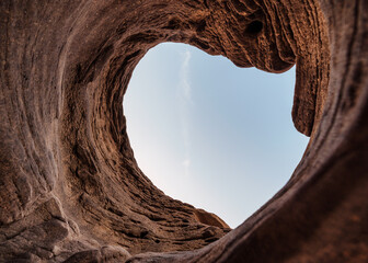 Natural stone hole cave of eroded surface by water with blue sky in national park - obrazy, fototapety, plakaty