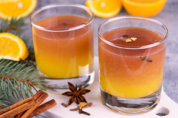 Hot mulled wine apple cider with spices in glasses on a white plate.
Close-up.