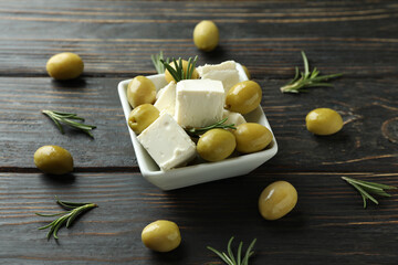 Bowl with feta cheese, olives and rosemary on wooden background