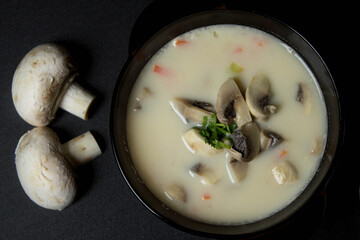 Plate with soup on a black background. Mushroom soup. Background. Appetizing soup.