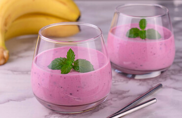 
Berry smoothie with banana on a marble background.
Close-up.