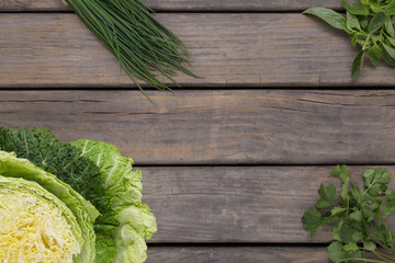Fototapeta premium overhead view of rustic wood base with green cabbage, chives, basil and coriander