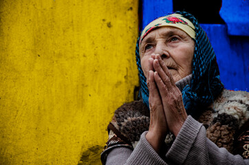 Grandmother prays on a yellow background close-up. An elderly woman in prayer. An old grandmother...