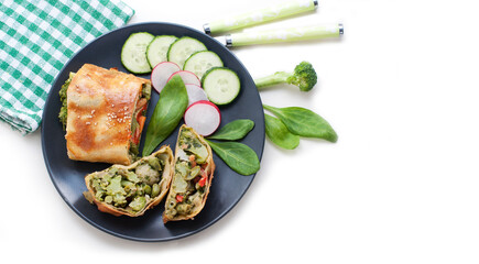 Strudel with broccoli, spinach, carrot, cauliflower and knife on white background. Top view
