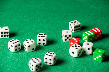 Top view of white, green and red dice on green playing mat, selective focus, horizontal, with copy space