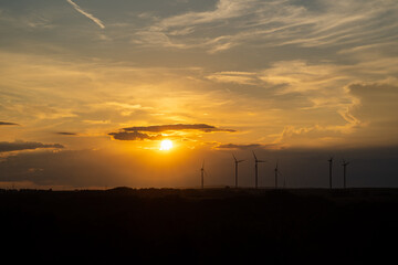Sunset in landscape over wind turbine farm