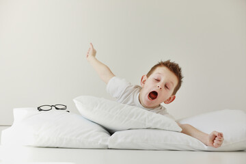 child boy wakes up and stretching on his comfortable bed in morning, Health care and good morning world concept. Stretches and yawns.