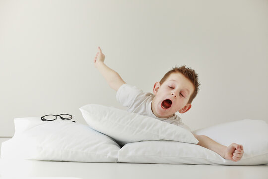 child boy wakes up and stretching on his comfortable bed in morning, Health care and good morning world concept. Stretches and yawns.
