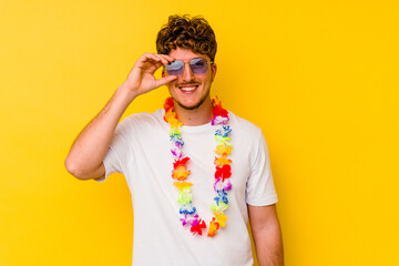 Young caucasian man wearing a Hawaiian party stuff isolated on yellow background excited keeping ok...