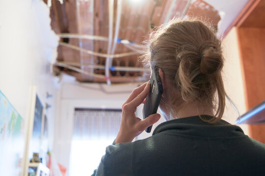 Woman talking to homeowner's insurer while inspecting kitchen ceiling