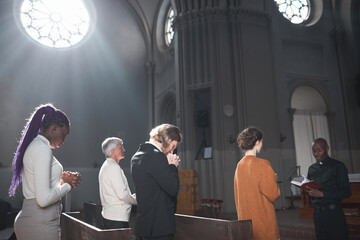 Group of people standing in the church during a mass with priest