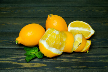lemons with mint leaves on a dark wooden background
