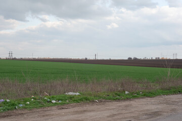 trash roadside minimalistic village landscape green grass field polluted with waste plastic roadside