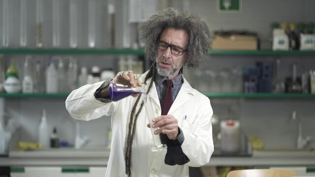 Science Professor pouring smokey liquid into flask. Funny Mad scientist experimenting with chemistry formula  in the lab
