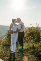 Newlyweds hug and kiss on the background of the forest. A man hugs and kisses a woman