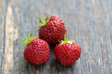 Harvested three fresh raw red ripened strawberries background, group of fruits with green stems