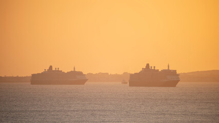 Obraz premium WEYMOUTH, DORSET, 3 APRIL 2021 - P&O Cruise Ship leaving Weymouth during glorious orange peaceful sunset