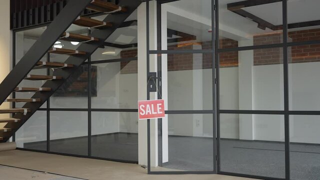 Wide shot of luxurious empty new apartment or office with Sale sign. Comfortable interiors with glass wall and ladder up indoors. Real estate and mortgage concept