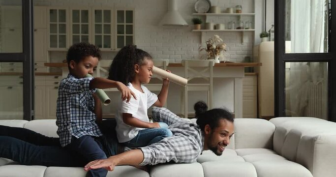 Overjoyed little cute african american brother and sister sitting on father, playing imagination creative pirates game. Sincere happy different generations mixed race family having fun at home.