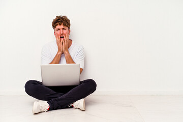 Young caucasian man sitting on the floor holding on laptop isolated on white background whining and crying disconsolately.